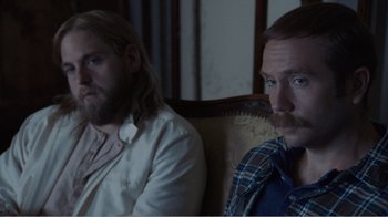 Movie still from “Don't Worry, He Won't Get Far on Foot” (2018), directed by Gus Van Sant – Two men sitting on a couch in a living room; Close Up shot, Over the shoulder angle