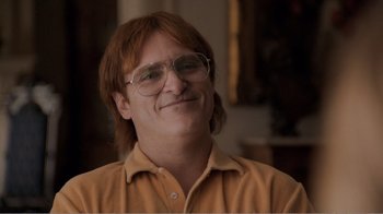 Movie still from “Don't Worry, He Won't Get Far on Foot” (2018), directed by Gus Van Sant – A man with glasses is smiling for the camera; Close Up shot, Over the shoulder angle