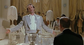 Movie still from “Life Is Beautiful” (1997), directed by Roberto Benigni – A man standing in front of a table holding a wine glass; Medium shot, Low angle