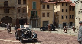 Movie still from “Life Is Beautiful” (1997), directed by Roberto Benigni – A couple of old cars parked on a brick road; Extreme Wide shot, High angle