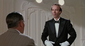 Movie still from “Life Is Beautiful” (1997), directed by Roberto Benigni – A man in a tuxedo talking to another man in white gloves; Medium shot, Low angle