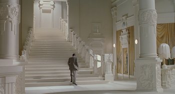 Movie still from “Life Is Beautiful” (1997), directed by Roberto Benigni – A man in a suit standing in front of a staircase; Extreme Wide shot, Low angle