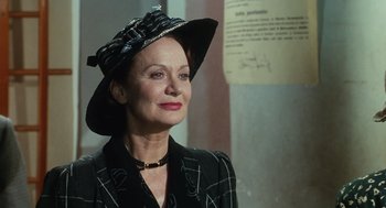Movie still from “Life Is Beautiful” (1997), directed by Roberto Benigni – An older woman wearing a hat and a black jacket; Close Up shot, Low angle