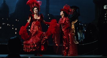 Movie still from “Life Is Beautiful” (1997), directed by Roberto Benigni – A couple of people that are dressed up in red; Wide shot, Low angle