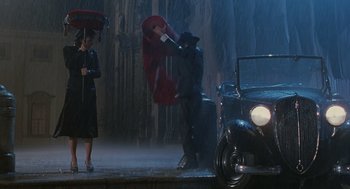 Movie still from “Life Is Beautiful” (1997), directed by Roberto Benigni – A man and a woman in the rain with an umbrella; Wide shot, High angle