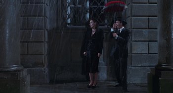 Movie still from “Life Is Beautiful” (1997), directed by Roberto Benigni – A man and a woman standing next to each other under an umbrella; Wide shot, High angle