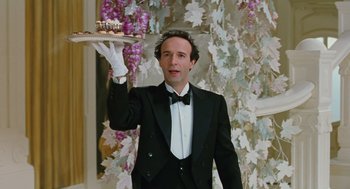 Movie still from “Life Is Beautiful” (1997), directed by Roberto Benigni – A man in a tuxedo holding a tray of food in his hand; Medium shot, Low angle