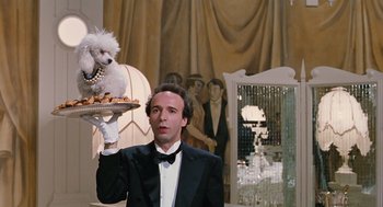 Movie still from “Life Is Beautiful” (1997), directed by Roberto Benigni – A man in a tuxedo holding a tray of food with a dog on top of it; Medium shot, Low angle