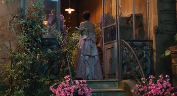 Movie still from “Life Is Beautiful” (1997), directed by Roberto Benigni – A woman in a dress standing in front of a door way; Wide shot, Over the shoulder angle