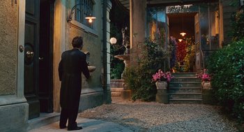 Movie still from “Life Is Beautiful” (1997), directed by Roberto Benigni – A man standing in front of a building with flowers; Wide shot, Over the shoulder angle