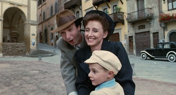 Movie still from “Life Is Beautiful” (1997), directed by Roberto Benigni – A man , woman , and a boy pose for a picture; Medium shot, High angle