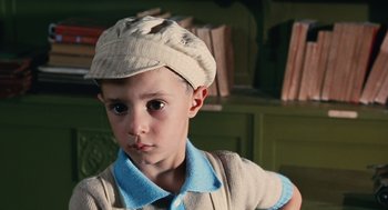 Movie still from “Life Is Beautiful” (1997), directed by Roberto Benigni – A young boy wearing a hat and a blue shirt; Close Up shot, High angle