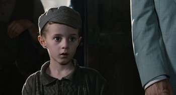 Movie still from “Life Is Beautiful” (1997), directed by Roberto Benigni – A young boy wearing a hat and a sweater; Close Up shot, Over the shoulder angle