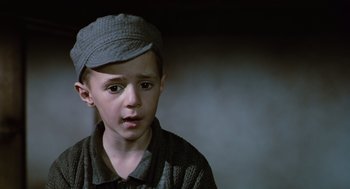 Movie still from “Life Is Beautiful” (1997), directed by Roberto Benigni – A young boy wearing a hat and looking sad; Close Up shot, Low angle