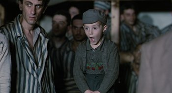 Movie still from “Life Is Beautiful” (1997), directed by Roberto Benigni – A young boy wearing a hat and a gray shirt; Medium shot, Over the shoulder angle