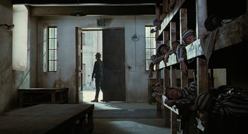 Movie still from “Life Is Beautiful” (1997), directed by Roberto Benigni – A man standing in front of a room filled with shelves; Wide shot, High angle