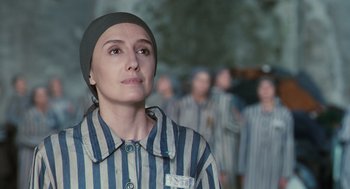 Movie still from “Life Is Beautiful” (1997), directed by Roberto Benigni – A group of women in striped clothing in a prison yard; Medium shot, Over the shoulder angle