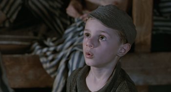 Movie still from “Life Is Beautiful” (1997), directed by Roberto Benigni – A young boy wearing a hat and a sweater; Close Up shot, Low angle