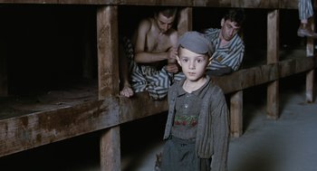 Movie still from “Life Is Beautiful” (1997), directed by Roberto Benigni – A young boy standing next to two men in a prison cell; Medium shot, High angle