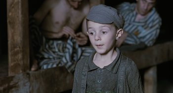 Movie still from “Life Is Beautiful” (1997), directed by Roberto Benigni – A young boy wearing a hat and a sweater; Medium shot, High angle