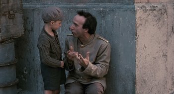 Movie still from “Life Is Beautiful” (1997), directed by Roberto Benigni – A man and a boy are sitting next to each other; Medium shot, Over the shoulder angle