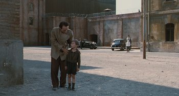 Movie still from “Life Is Beautiful” (1997), directed by Roberto Benigni – A man and a boy standing on a street; Wide shot, Over the shoulder angle