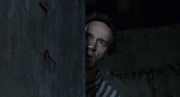 Movie still from “Life Is Beautiful” (1997), directed by Roberto Benigni – A man in striped shirt standing next to a concrete wall; Close Up shot, Low angle