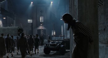 Movie still from “Life Is Beautiful” (1997), directed by Roberto Benigni – A group of people walking around in a dark place; Wide shot, Low angle