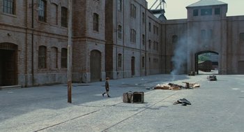 Movie still from “Life Is Beautiful” (1997), directed by Roberto Benigni – A young boy walking down the street in front of an old brick building; Extreme Wide shot, High angle