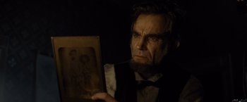 Movie still from “Lincoln” (2012), directed by Steven Spielberg – A man in a vest and bow tie holding a picture; Close Up shot, Over the shoulder angle