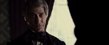 Movie still from “Lincoln” (2012), directed by Steven Spielberg – An older man wearing a suit and bow tie in front of a window; Close Up shot, Over the shoulder angle