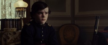 Movie still from “Lincoln” (2012), directed by Steven Spielberg – A boy in a uniform sitting in front of a chair; Close Up shot, Over the shoulder angle
