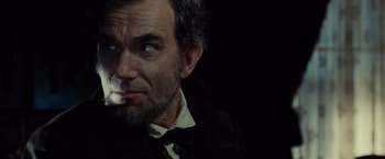 Movie still from “Lincoln” (2012), directed by Steven Spielberg – A man with a beard and a mustache smoking a cigarette; Close Up shot, Over the shoulder angle
