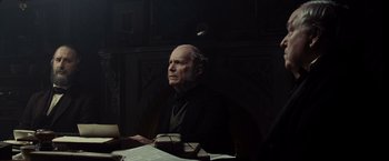 Movie still from “Lincoln” (2012), directed by Steven Spielberg – An older man sitting at a table in a dark room; Medium shot, Over the shoulder angle