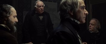 Movie still from “Lincoln” (2012), directed by Steven Spielberg – An older man in a suit and tie talking to another older man; Medium shot, Over the shoulder angle