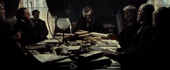 Movie still from “Lincoln” (2012), directed by Steven Spielberg – A man sitting at a table with a lot of papers; Medium shot, High angle