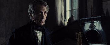 Movie still from “Lincoln” (2012), directed by Steven Spielberg – An older man in a suit and bow tie looking at the camera; Close Up shot, Low angle