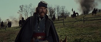 Movie still from “Lincoln” (2012), directed by Steven Spielberg – A man in a civil war uniform standing next to a horse; Medium shot, Over the shoulder angle