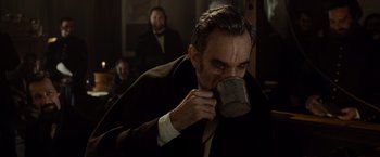 Movie still from “Lincoln” (2012), directed by Steven Spielberg – A man drinking from a cup in a dark room; Close Up shot, Over the shoulder angle