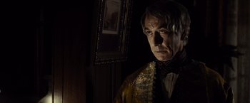 Movie still from “Lincoln” (2012), directed by Steven Spielberg – A man standing in front of a painting in a dark room; Close Up shot, Over the shoulder angle