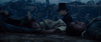 Movie still from “Lincoln” (2012), directed by Steven Spielberg – A man wearing a top hat and a black coat is standing over a dead body; Close Up shot, Over the shoulder angle