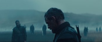 Movie still from “Macbeth” (2015), directed by Justin Kurzel – A person in a field near a body of water; Medium shot, Over the shoulder angle