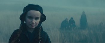 Movie still from “Macbeth” (2015), directed by Justin Kurzel – A young girl in a black hat and a group of people in a field; Close Up shot, Low angle