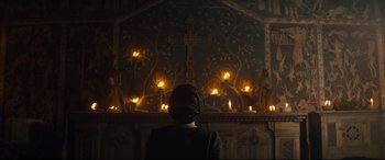 Movie still from “Macbeth” (2015), directed by Justin Kurzel – A person standing in front of a cross lit up with candles; Wide shot, Low angle