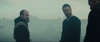 Movie still from “Macbeth” (2015), directed by Justin Kurzel – Two men standing in front of a mountain in the fog; Medium shot, Over the shoulder angle