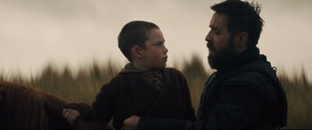 Movie still from “Macbeth” (2015), directed by Justin Kurzel – A man and a boy standing next to each other; Medium shot, Over the shoulder angle