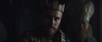 Movie still from “Macbeth” (2015), directed by Justin Kurzel – A man with a beard wearing a crown; Close Up shot, Over the shoulder angle