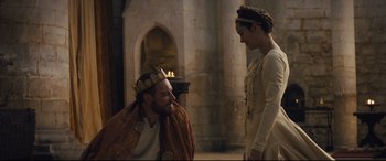 Movie still from “Macbeth” (2015), directed by Justin Kurzel – A man and a woman in medieval garb in front of a fire place; Medium shot, Over the shoulder angle