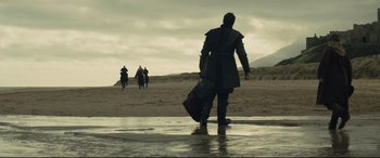 Movie still from “Macbeth” (2015), directed by Justin Kurzel – A man with a suitcase walking on the beach; Wide shot, Low angle