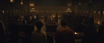 Movie still from “Macbeth” (2015), directed by Justin Kurzel – A group of people standing in a dark room; Extreme Wide shot, High angle